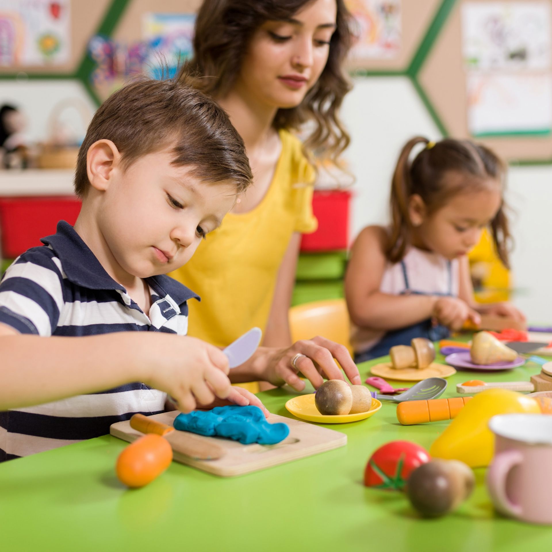 Young boy playing with kitchen toys in class