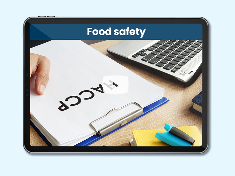 Desk with computer and white paper on which is written HACCP. Text on photo: Food Safety