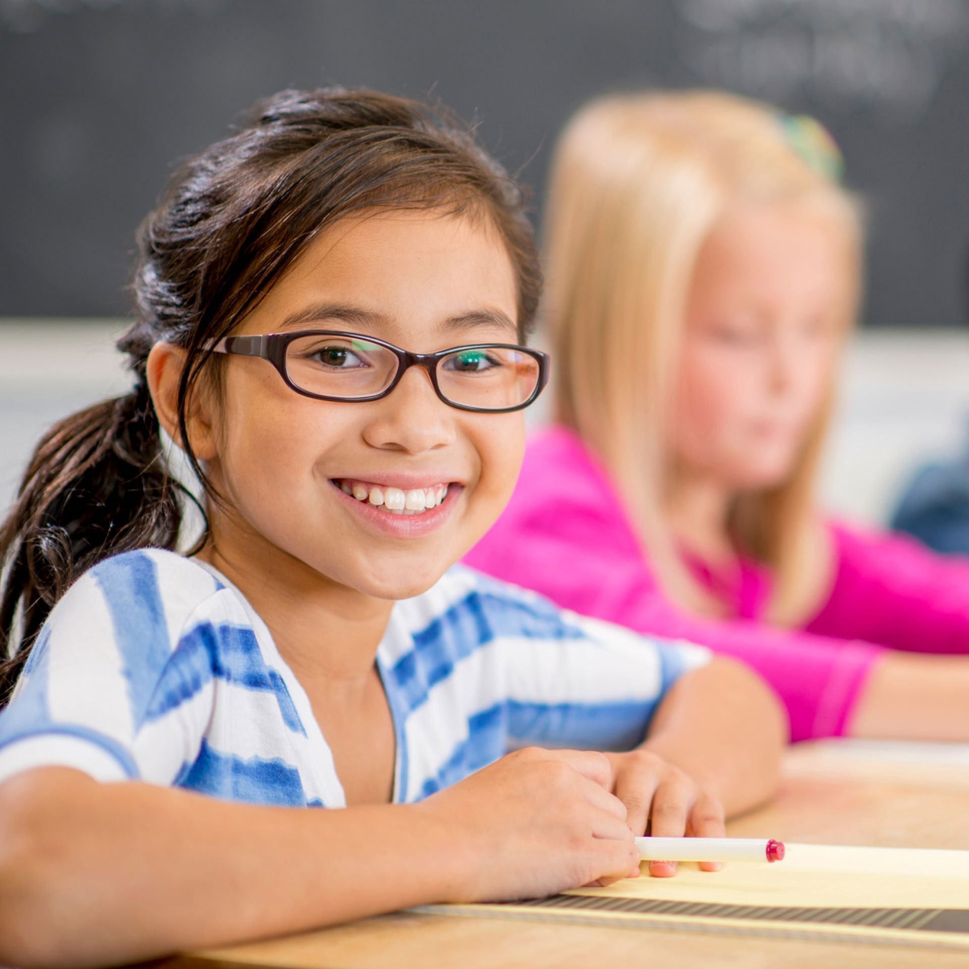 Young girl wearing glasses smiles in classe